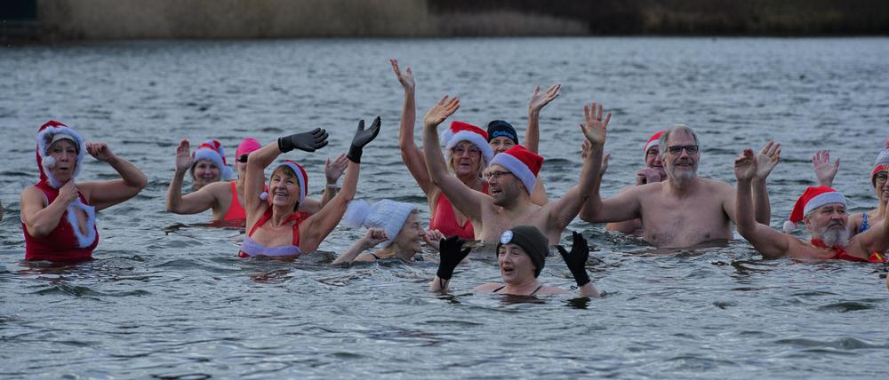 Teilnehmer winken beim  Weihnachts-Eisbaden der Berliner Seehunde 
