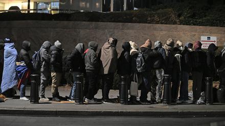 Migranten stehen in einer Schlange und warten, um mit Mitarbeitern der Einwanderungsbehörde zu sprechen.