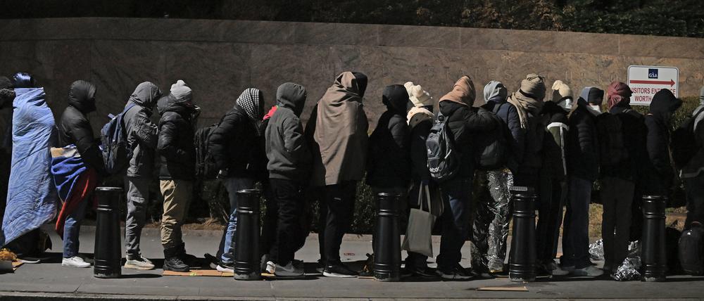 Migranten stehen in einer Schlange und warten, um mit Mitarbeitern der Einwanderungsbehörde zu sprechen.