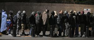 Migranten stehen in einer Schlange und warten, um mit Mitarbeitern der Einwanderungsbehörde zu sprechen.