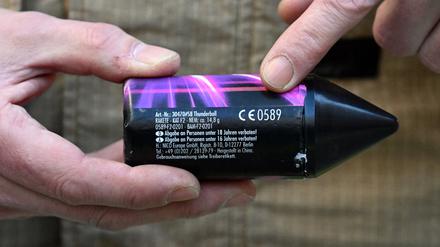 Ein Pyrotechniker der Feuerwehr hält eine Rakete der Kategorie F2 vom Typ „Thunderball“ in der Hand.