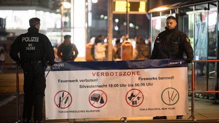 Berlin, Silvester 2023: Polizeibeamte stehen an der Böllerverbotszone am Alexanderplatz an einem Hinweisschild. 