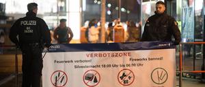 31.12.2023, Berlin: Polizeibeamte stehen an der Böllerverbotszone am Alexanderplatz an einem Hinweisschild. Neben dem Alexanderplatz, sind auch im Steinmetzkiez und rund um die Sonnenallee Verbotszonen eingerichtet. Foto: Sebastian Christoph Gollnow/dpa +++ dpa-Bildfunk +++