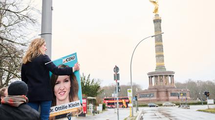 02.01.2024, Berlin: Ottilie Klein (CDU), Direktkandidatin für den Wahlkreis Berlin-Mitte und Generalsekretärin, hängt ein Plakat mit ihrem Konterfei vor der Siegessäule auf. In Berlin muss die Bundestagswahl in einigen Stimmbezirken wiederholt werden. Foto: Annette Riedl/dpa +++ dpa-Bildfunk +++