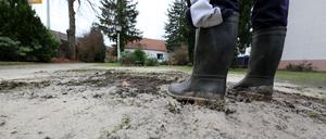 Eine Person steht im Gummistiefeln im Vorgarten. Ein Rohrbruch flutete das Grundstück in der Neuendorfer Straße.