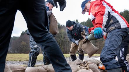 In Thüringen befestigen Feuerwehrleute und Helfer einen Damm. 