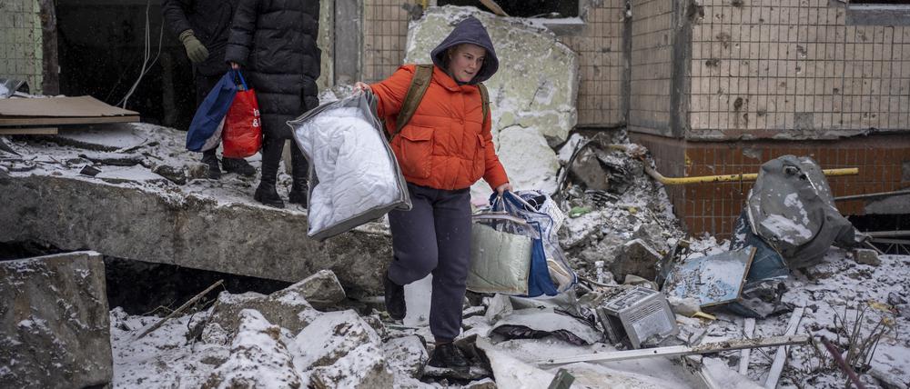 Eine Frau trägt ihre Habseligkeiten aus einer Wohnung, die durch einen russischen Angriff zerstört wurde. 