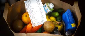 Ein Kassenbon liegt auf den Lebensmitteln in einer Einkaufstüte.