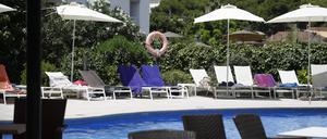 Handtücher liegen auf Sonnenliegen an einem Pool. 