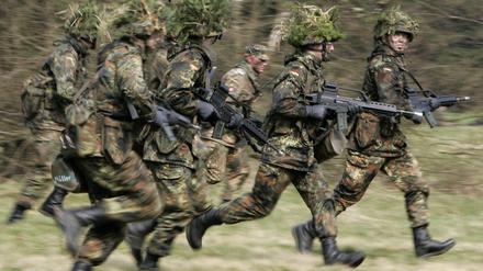 Hessen, Schwarzenborn: Mit Blattwerk und Gras getarnte Wehrpflichtige von den Panzergrenadieren rennen im Rahmen ihrer Grundausbildung über das freie Gelände der Knüll Kaserne in Schwarzenborn (Schwalm-Eder-Kreis). 