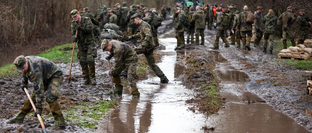 Soldatinnen und Soldaten der Bundeswehr sichern einen Deich an der Helme mit Sandsäcken.