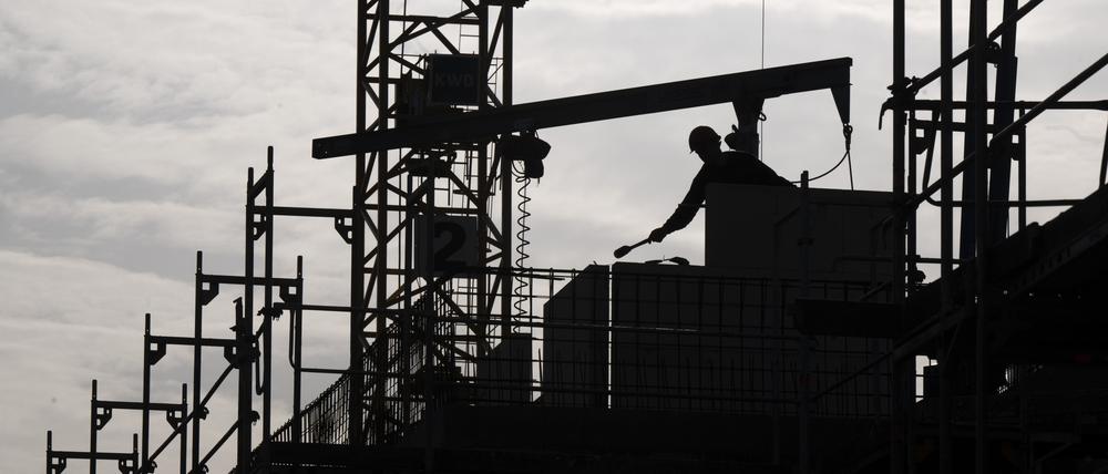 Ein Bauarbeiter arbeitet auf einer Baustelle von einem neu gebauten Wohnhaus.