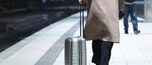 Eine Frau geht mit ihrem Reisekoffer auf einem Bahnsteig am Hauptbahnhof Hamburg entlang.