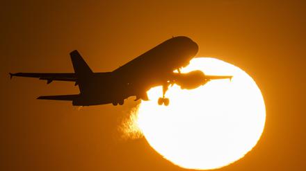 Eine Passagiermaschine hebt vor der untergehenden Sonne vom Flughafen Frankfurt ab. 