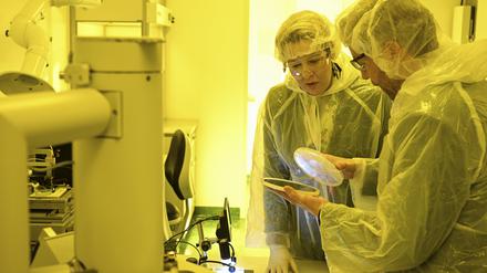 Wirtschaftssenatorin Franziska Giffey lässt sich vom technischen Leiter Arne Schleunitz die Produktion von Chips erklären. Das gelbe Licht im Reinraum schützt die Chemikalien.