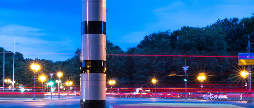 ARCHIV - 26.07.2023, Berlin: Eine Blitzsäule steht am Kreisverkehr an der Siegessäule, während im Hintergrund vorbeifahrende Fahrzeuge Lichtspuren hinterlassen (Aufnahme mit Langzeitbelichtung). (zu: «Weitere Blitzer in Berlin - wenig Wirkung auf Autofahrer») Foto: Monika Skolimowska/dpa +++ dpa-Bildfunk +++
