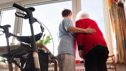 Eine Seniorin wird von einer Pflegekraft gestützt. (Symbolbild)