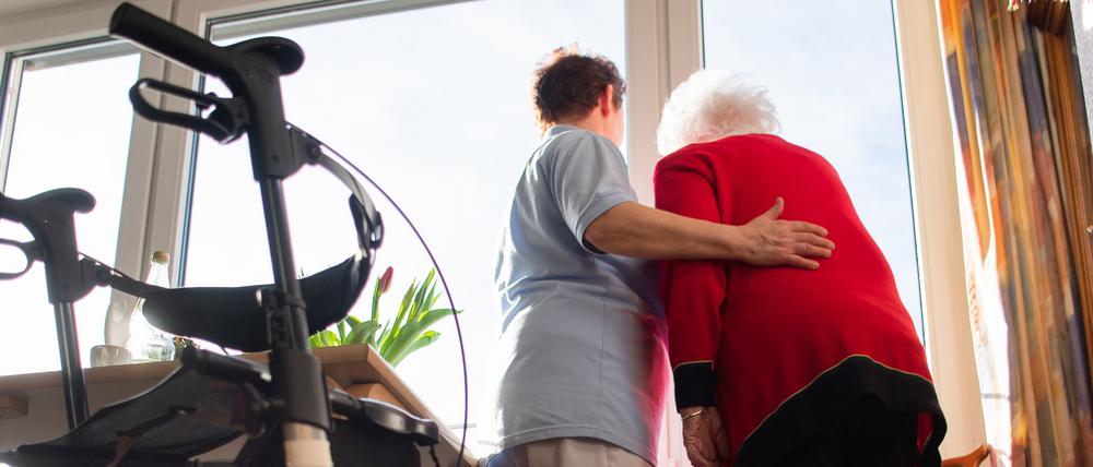 Eine Seniorin wird von einer Pflegekraft gestützt. (Symbolbild)
