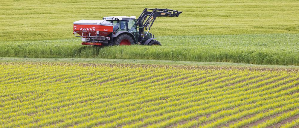 Landwirt beim Düngen seiner Felder mit dem Traktor.