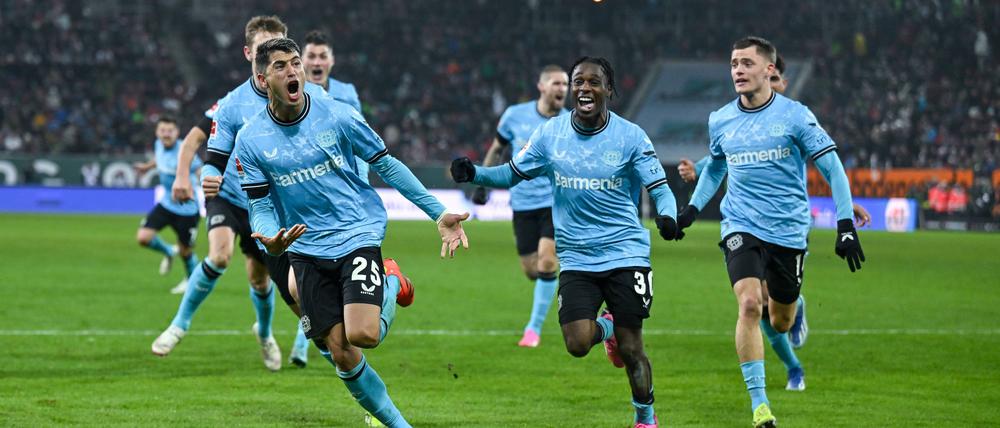 Exequiel Palacios bejubelt mit seinen Leverkusener Kollegen den späten Siegtreffer in Augsburg.