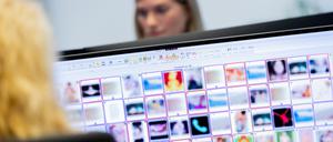 Ermittlerinnen sitzen vor Monitoren mit unkenntlich gemachten Fotografien, die teilweise sexuellen Missbrauch zeigen.