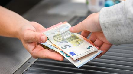 Eine Kassiererin gibt einer Kundin Wechselgeld an der Kasse eines Supermarktes.