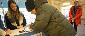 Freiwillige der Partei «Einiges Russland» (l) helfen Besuchern während einer Unterschriftensammlung für die Kandidatur des russischen Präsidenten Putin bei den Präsidentschaftswahlen im März im GUM-Kaufhaus in der Nähe des Roten Platzes. 