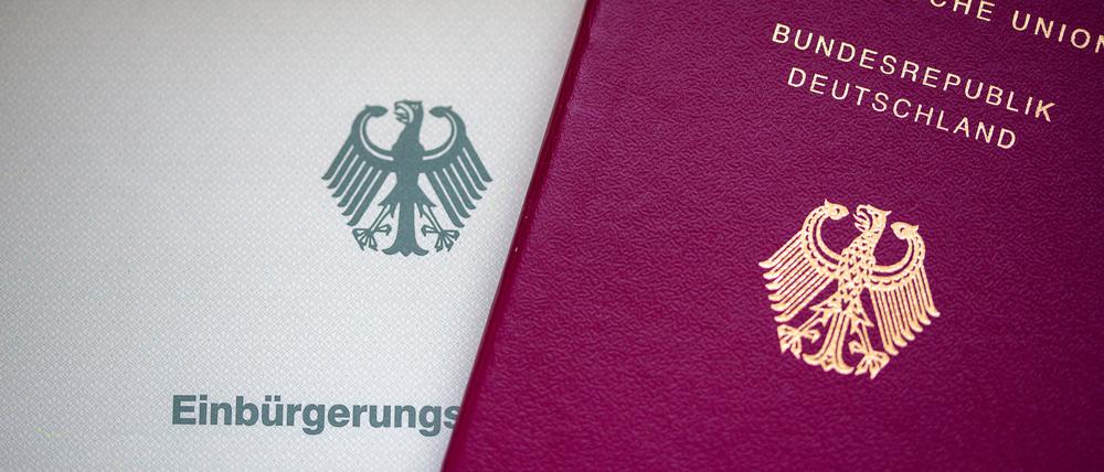 Eine Einbürgerungsurkunde der Bundesrepublik Deutschland und ein deutscher Reisepass liegen auf einem Tisch.  