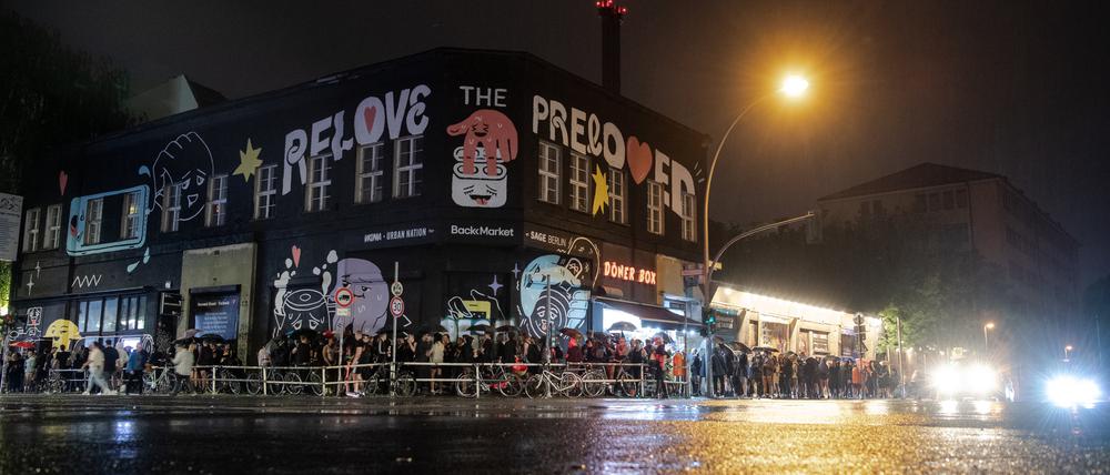 Menschen stehen im strömenden Regen dicht an dicht am Eingang zum Kitkat-Club.