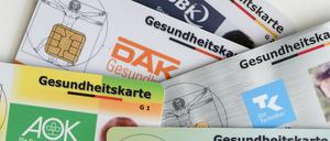Gesundheitskarten verschiedener Krankenkassen liegen auf einem Tisch. 