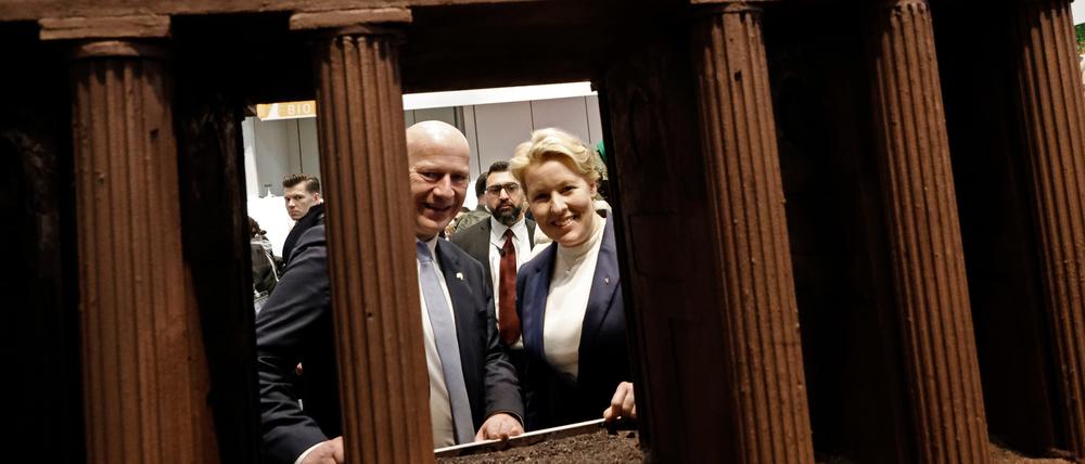 Kai Wegner (CDU), Regierender Bürgermeister von Berlin, und Franziska Giffey (SPD, r), Berliner Wirtschaftssenatorin, schauen beim Eröffnungsrundgang über das Messegelände der Grünen Woche in der Berlin Halle durch ein großes Brandenburger Tor aus Schokolade.