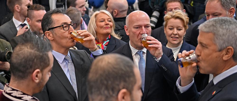 Cem Özdemir (Bündnis 90/Die Grünen, l), Bundesminister für Ernährung und Landwirtschaft, und Kai Wegner (CDU, 3.v.r), Regierender Bürgermeister von Berlin, trinken beim Eröffnungsrundgang über das Messegelände der Grünen Woche am Stand des Landes Marokko aus einem Glas. 