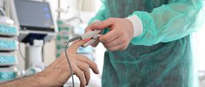 Ein Pfleger legt einem Patienten ein Messgerät an.