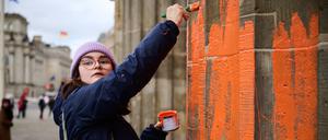 Eine Klimaaktivistin bemalt das Brandenburger Tor mit oranger Farbe. 