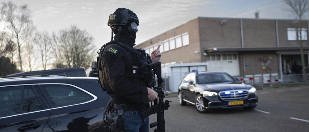 Maskierte und bewaffnete niederländische Polizisten bewachen einen Transport mit einigen der Verdächtigen, die vor dem Hochsicherheitsgebäude des Gerichts in Amsterdam eintreffen.