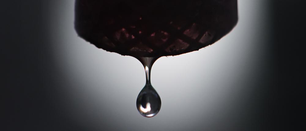 Grundwasser tropft aus einem Schlauch, der per Pumpe an einen Grundwasserbrunnnen angeschlossen ist. Weltweit sinken die Grundwasserstände, wie eine aktuelle Studie in der „Nature“ zeigt.
