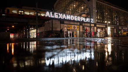 Menschen laufen am frühen Morgen vor dem Fernsehturm über den Alexanderplatz.