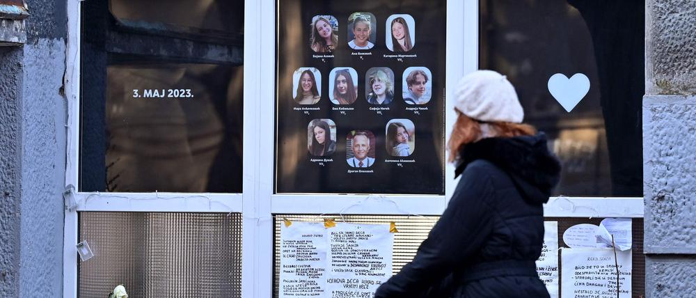 Eine Fußgängerin schiebt ihren Kinderwagen an der Schule in Belgrad vorbei, in der im Mai vergangenen Jahres ein 13-Jähriger neun Menschen erschoss. Im Fenster hängen Bild der Getöteten.