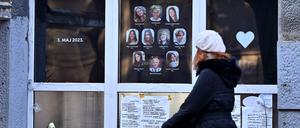 Eine Fußgängerin schiebt ihren Kinderwagen an der Schule in Belgrad vorbei, in der im Mai vergangenen Jahres ein 13-Jähriger neun Menschen erschoss. Im Fenster hängen Bild der Getöteten.