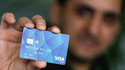 Ein Geflüchteter hält eine Debitcard in der Hand. Der Ortenaukreis zwischen Rhein und Schwarzwald will von diesem Dienstag an die ersten Bezahlkarten für Geflüchtete ausgeben.