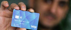 Ein Geflüchteter hält eine Debitcard in der Hand. Der Ortenaukreis zwischen Rhein und Schwarzwald will von diesem Dienstag an die ersten Bezahlkarten für Geflüchtete ausgeben.