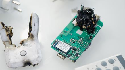 Eine verbrannte Funksteckdose liegt in einem Schaukasten der Bundesnetzagentur. Die Bundesnetzagentur hat den Verkauf der Geräte untersagt, weil eine thermische Schutzfunktion fehlt und es zum Brand der Geräte kommen kann.