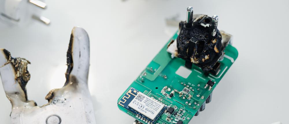 Eine verbrannte Funksteckdose liegt in einem Schaukasten der Bundesnetzagentur. Die Bundesnetzagentur hat den Verkauf der Geräte untersagt, weil eine thermische Schutzfunktion fehlt und es zum Brand der Geräte kommen kann.