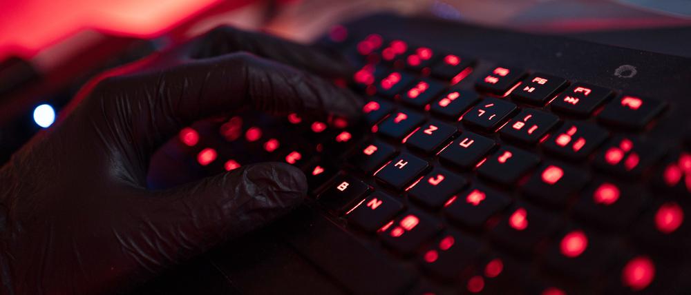 Ein Mann trägt Handschuhe und tippt auf einer Tastatur (Archivbild).