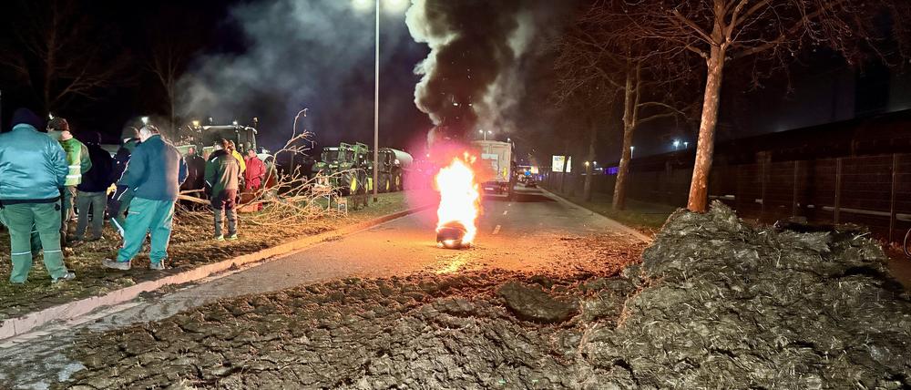 Landwirte blockieren mit Mist und brennenden Reifen eine Straße bei Magdeburg.