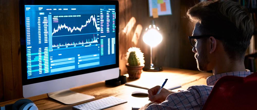 Ein junger Mann verfolgt am Computerbildschirm Aktienkurse.