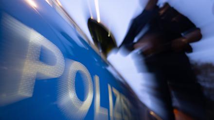 Eine Polizistin steht neben einem Polizeifahrzeug. 