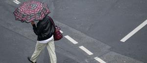 Mit einem Schirm schützt sich eine Passantin in Frankfurt vor dem strömenden Regen. 