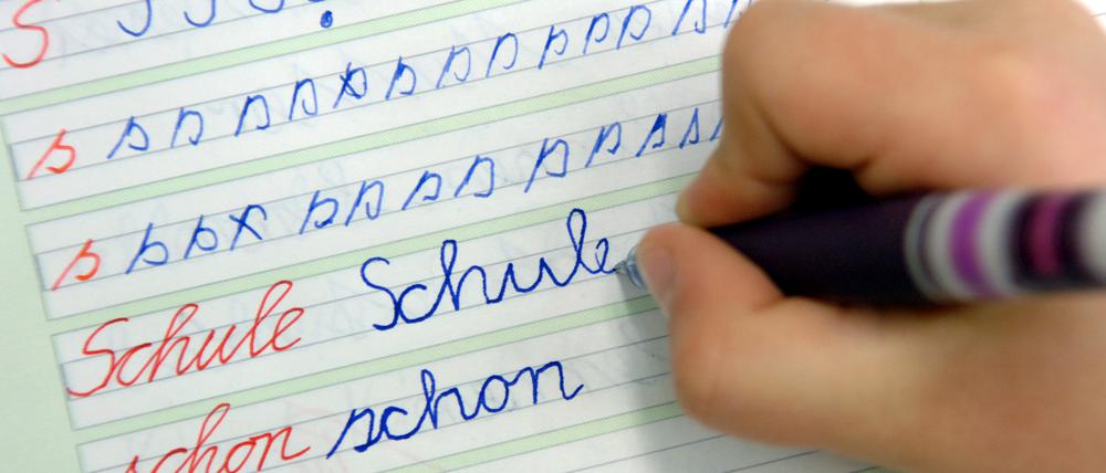 ARCHIV - 13.04.2005, Brandenburg, Görzig: In der Dorfschule schreibt ein Mädchen im Unterricht das Wort «Schule» in ihr Heft. (zu dpa «Zeugnisse in Berlin und Brandenburg trotzt Streiks gesichert») Foto: Patrick Pleul/dpa-Zentralbild/dpa +++ dpa-Bildfunk +++