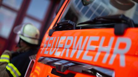 Ein Feuerwehrmann steht neben einem Einsatzfahrzeug (gestellte Szene)